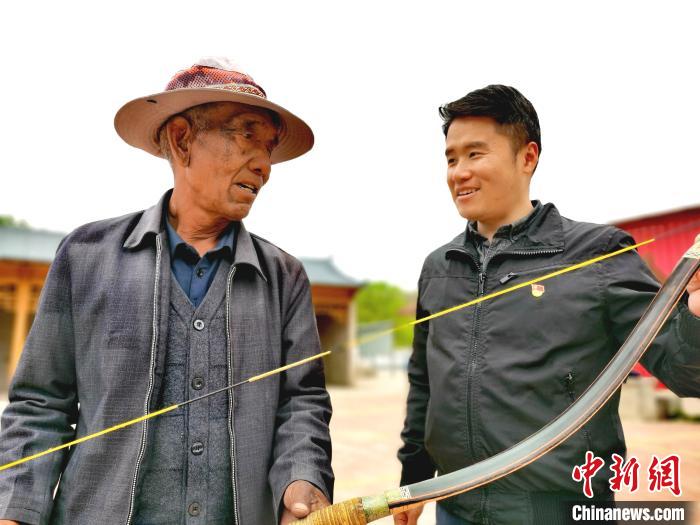 图为彭韬(右)和村里老人交流射箭技术。　张添福 摄