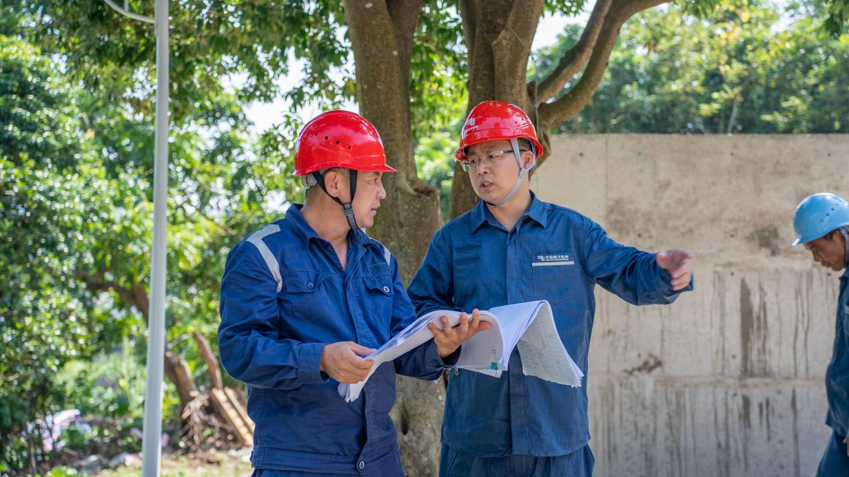 叶林青和施工人员在施工现场协调项目建设问题。广东电网公司供图