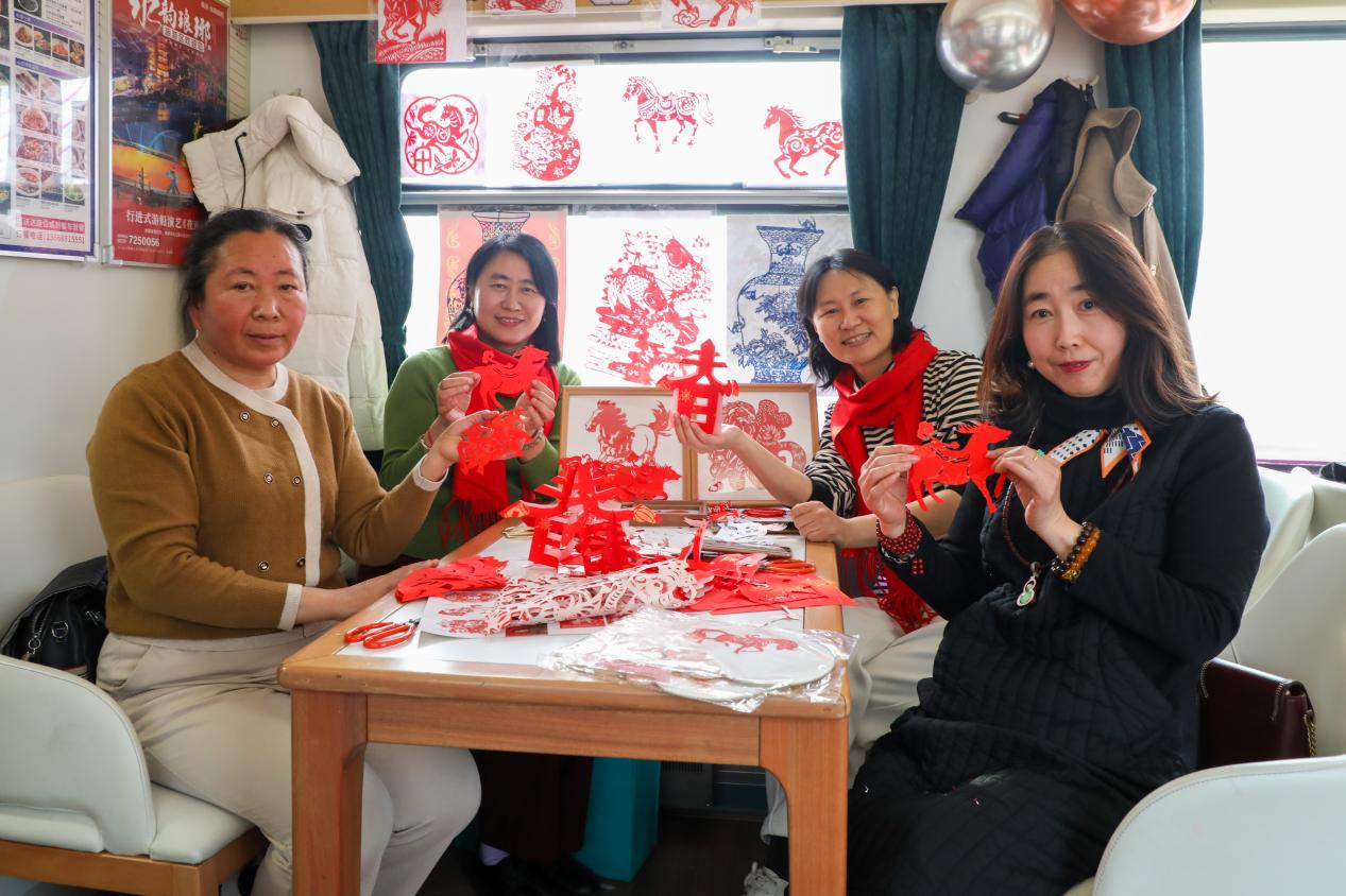 1月29日，乘客在“齐鲁1号·黄河大集”主题车厢体验凌氏剪纸。刘洋摄