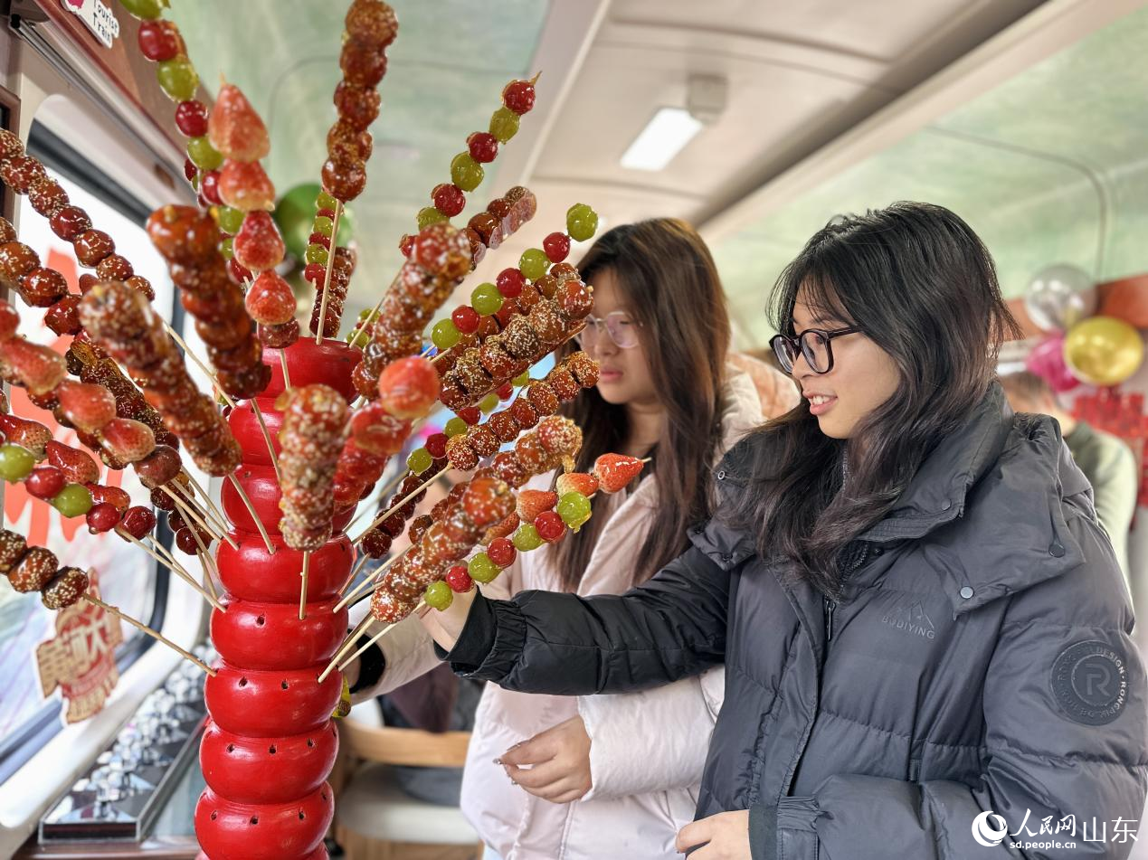 1月29日，在“齐鲁1号·黄河大集”主题车厢，乘客选购糖葫芦。人民网记者 乔姝摄